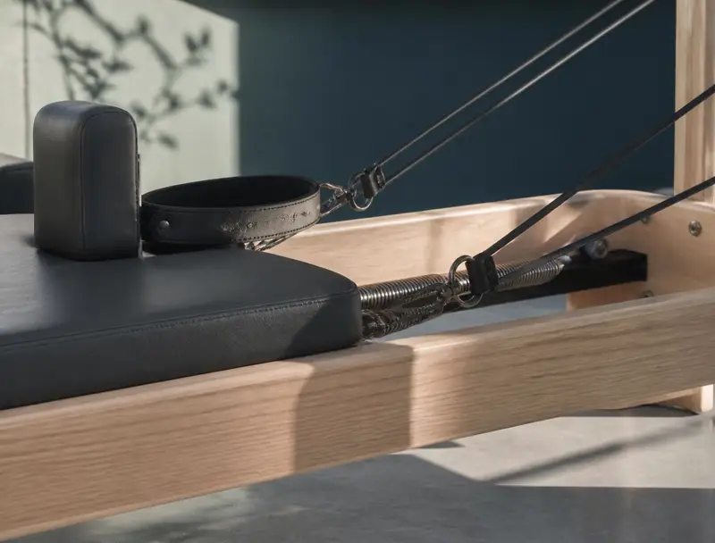 Timber reformer carriage with black leather straps and springs in morning light
